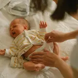 Mama zmienia pieluchę noworodkowi, zastanawiając się, jakie pieluchy dla noworodka będą najlepsze.