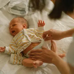 Mama zmienia pieluchę noworodkowi, zastanawiając się, jakie pieluchy dla noworodka będą najlepsze.