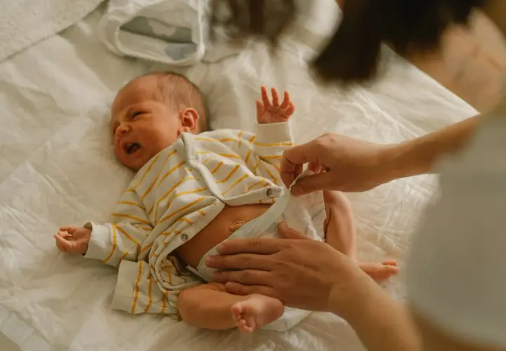 Mama zmienia pieluchę noworodkowi, zastanawiając się, jakie pieluchy dla noworodka będą najlepsze.